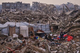Palestinians stand next to a tent set up on the rubble of buildings destroyed during Israeli air and ground operations in the Sheikh Radwan neighborhood, in Gaza City, Tuesday, Dec. 30, 2025. (AP Photo/Abdel Kareem Hana)